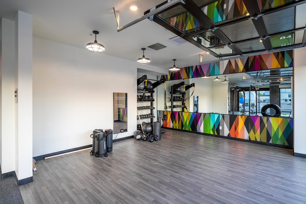 A gym with a mirrored wall and a wooden floor.