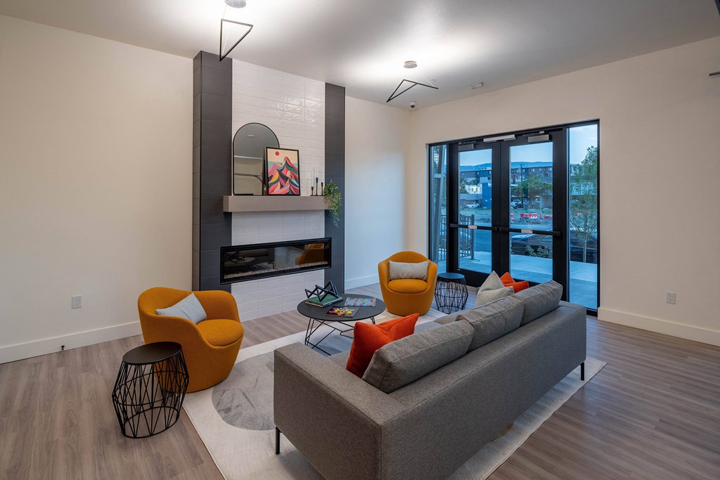 A living room with a grey couch, orange chairs, and a fireplace.
