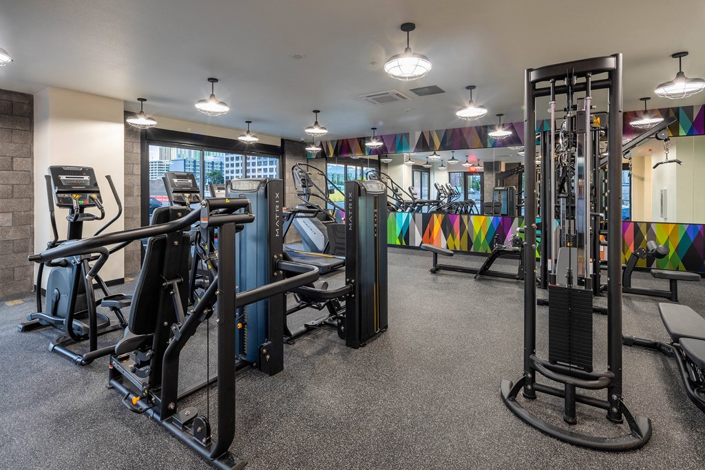 A gym with a variety of equipment including treadmills, weights, and exercise machines.