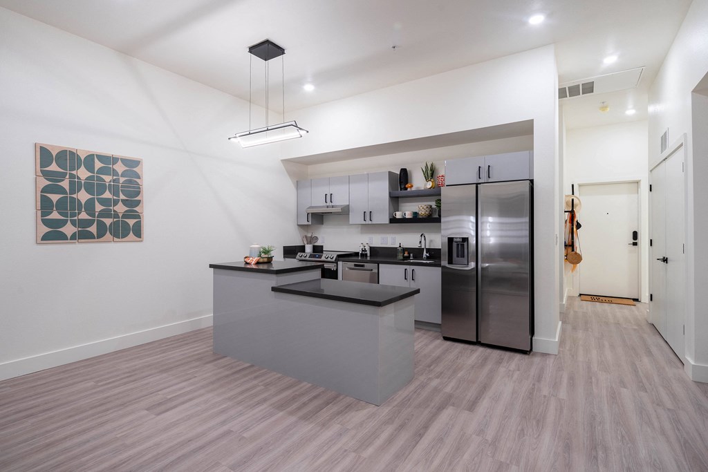 A modern kitchen with a grey countertop and stainless steel appliances.