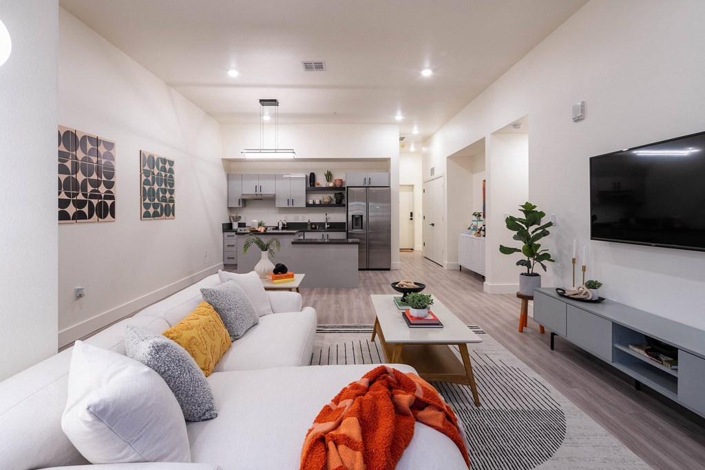 A modern living room with a white sofa and a television on the wall.