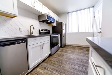 A kitchen with white cabinets and a black fridge.