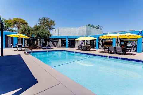 A pool with a blue tiled edge and yellow umbrellas.
