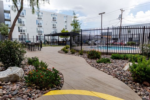 A walkway with a yellow line in the middle leads to a black fence and a pool.