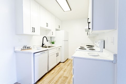 A white kitchen with wooden floors and white cabinets.