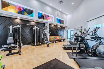 A gym with a variety of equipment including treadmills, weights, and exercise machines.
