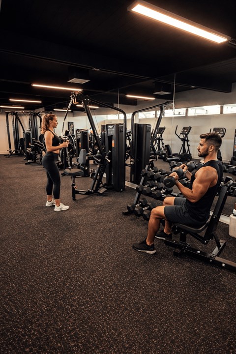 A man and a woman are working out in a gym.