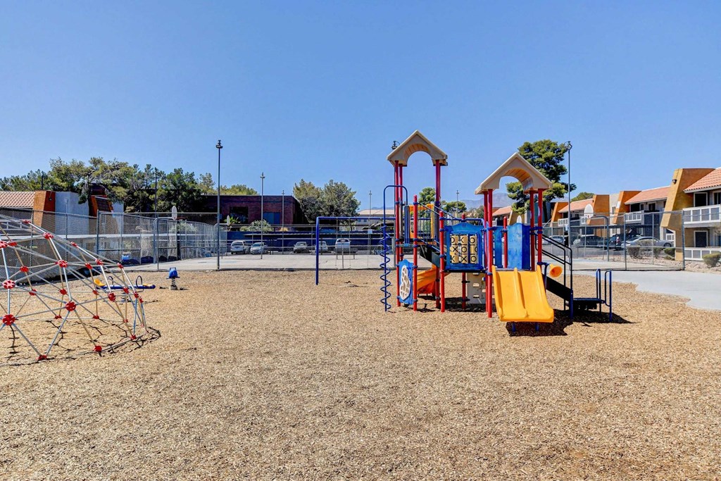 A playground with a yellow slide and red and blue play structures.