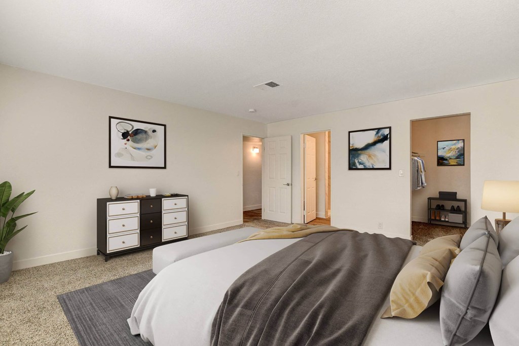 A bedroom with a bed, nightstands, and pictures on the wall.