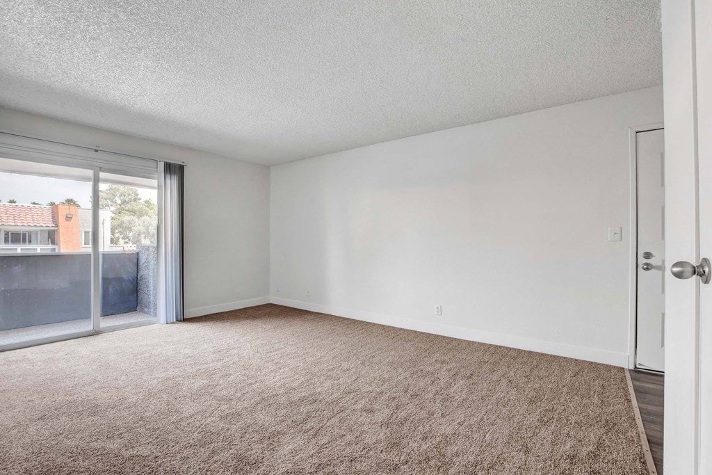 Empty room with carpeted floor and sliding glass doors.