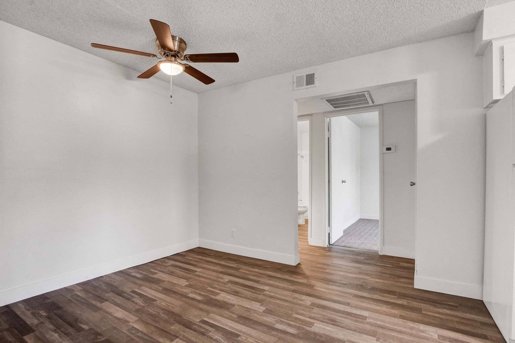A room with a ceiling fan and wooden flooring.