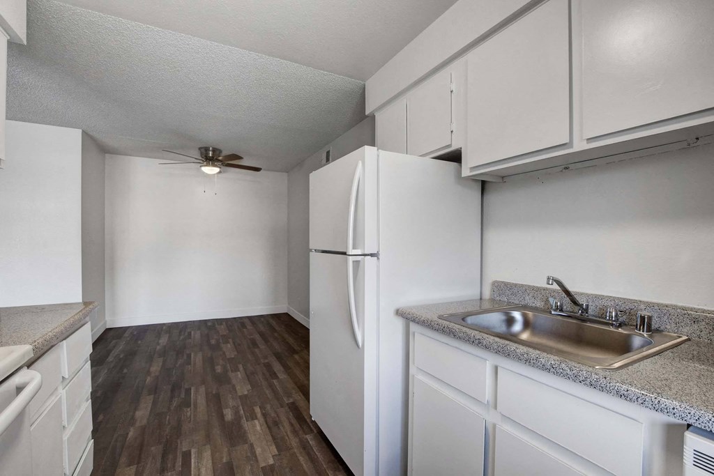 A kitchen with a white refrigerator and a sink.