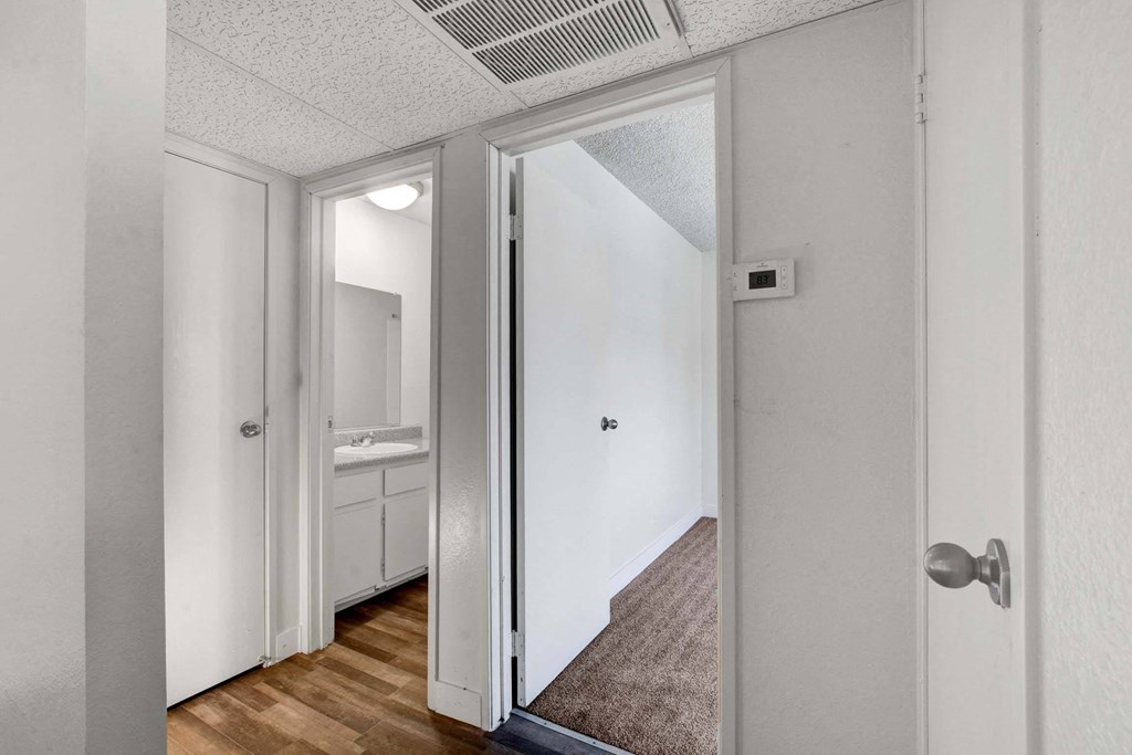 A hallway with a white door and a brown carpet.