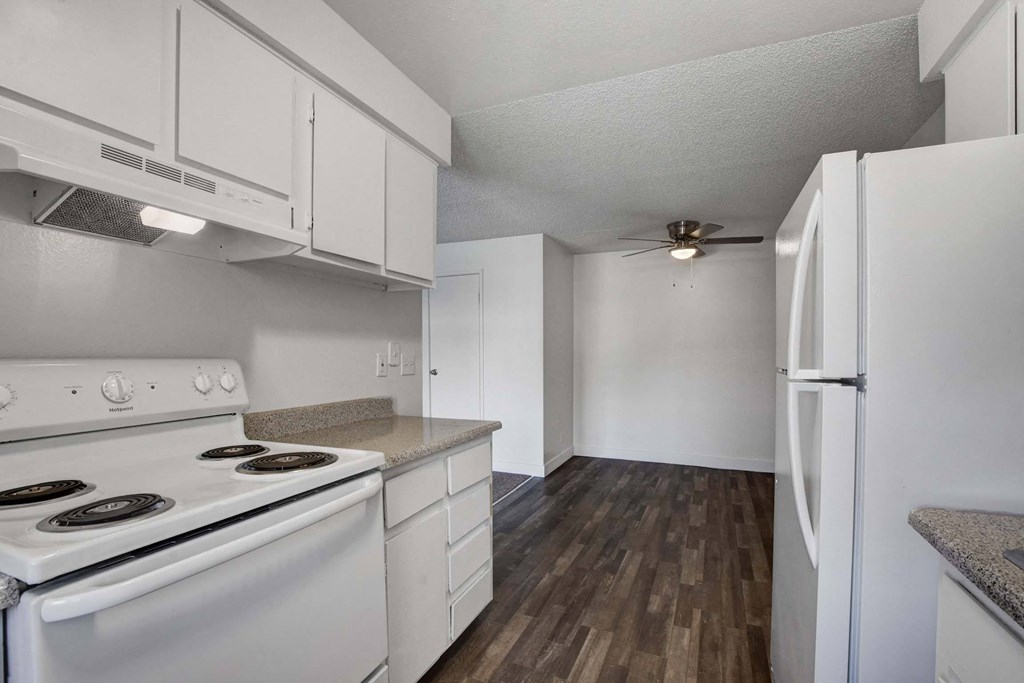 A kitchen with white appliances and wooden floors.