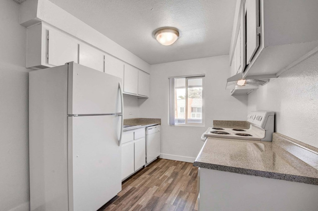 A kitchen with white appliances and a window.