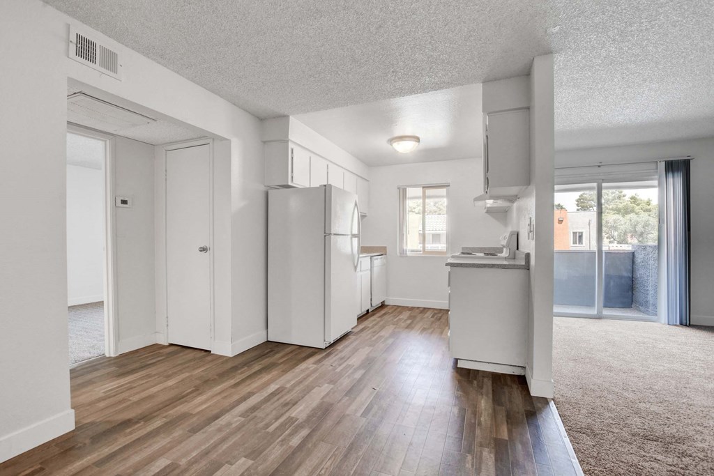 A kitchen with white appliances and wooden floors.