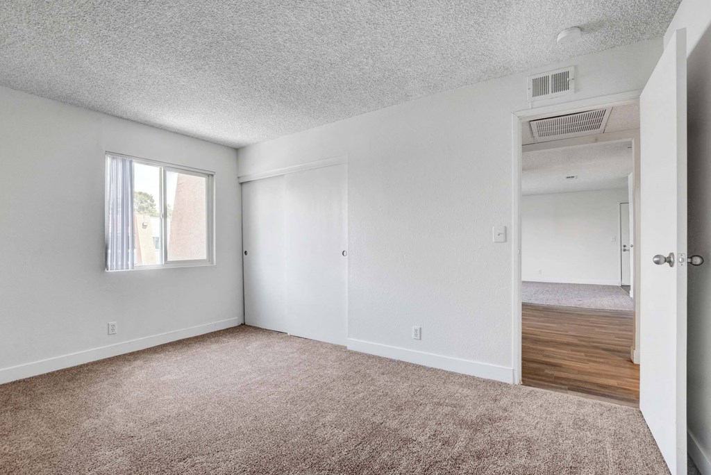A room with a carpeted floor and a window with blinds.