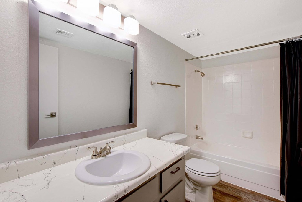 A bathroom with a marble countertop and a white sink.