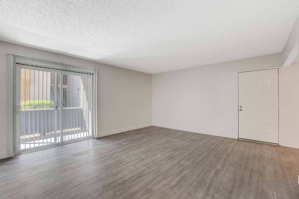 A room with a sliding glass door and a wooden floor.