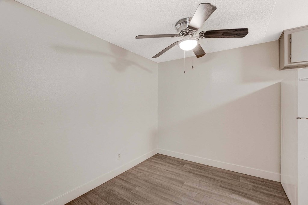 A room with a ceiling fan and wooden flooring.