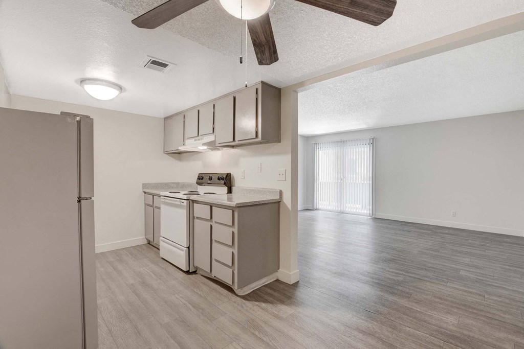 A kitchen with a refrigerator, dishwasher, and a ceiling fan.