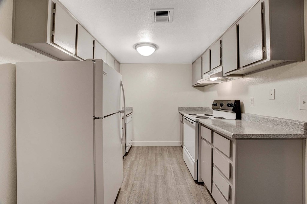 A kitchen with a white refrigerator and a white counter top.
