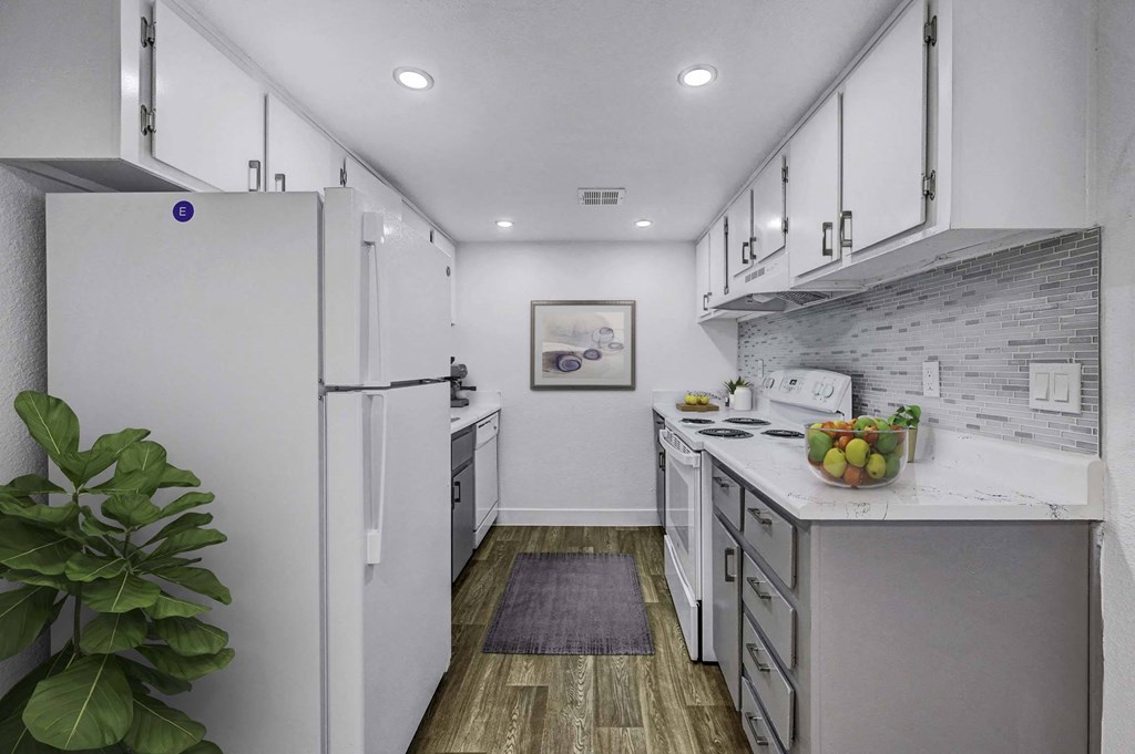 A modern kitchen with white cabinets and a wooden floor.