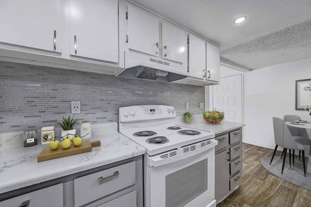 A modern kitchen with a white stove top oven and a wooden cutting board with lemons on it.