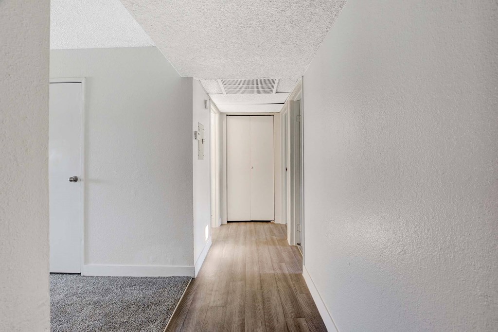 A long hallway with white walls and wood flooring.