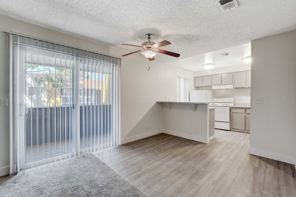 A room with a ceiling fan and sliding glass doors.