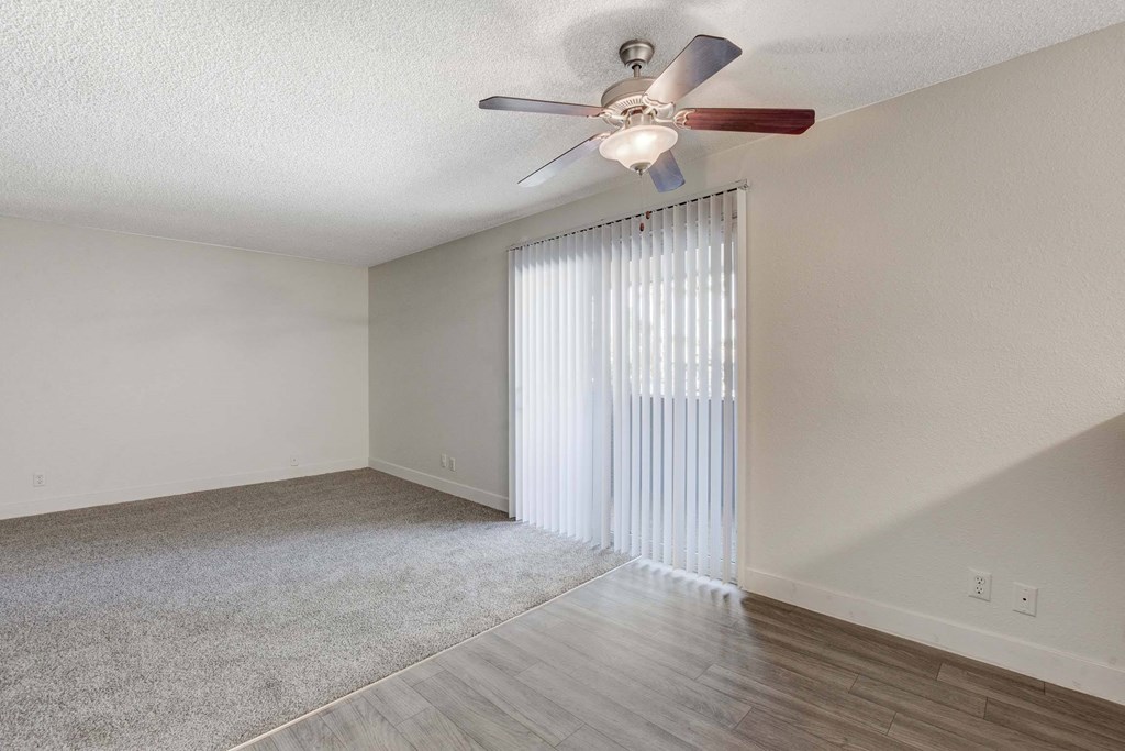 A room with a ceiling fan and a window with blinds.