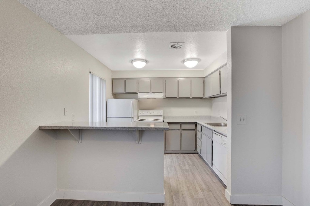 A kitchen with white cabinets and a refrigerator.