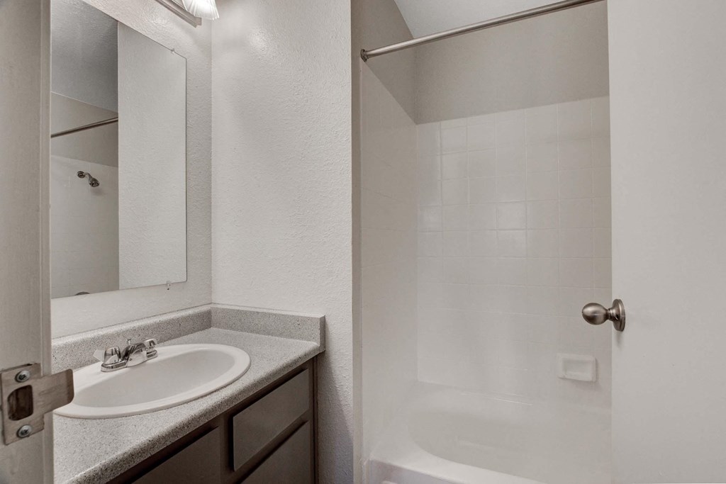 A white bathroom with a sink and a shower.