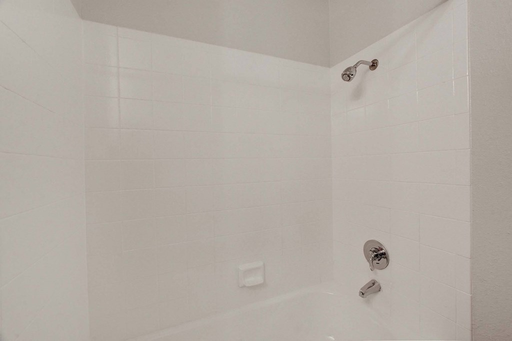 A white bathroom with a shower and faucet.