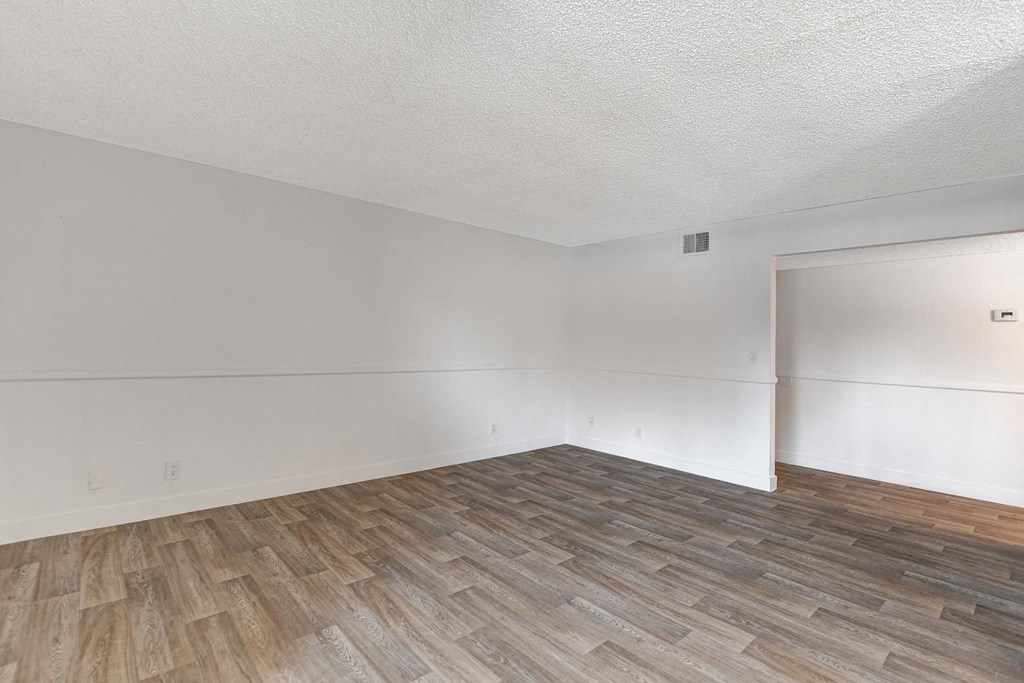 A room with wooden flooring and white walls.