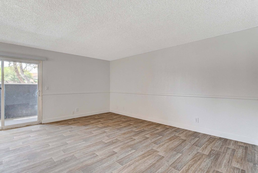 A room with wooden flooring and a sliding glass door.