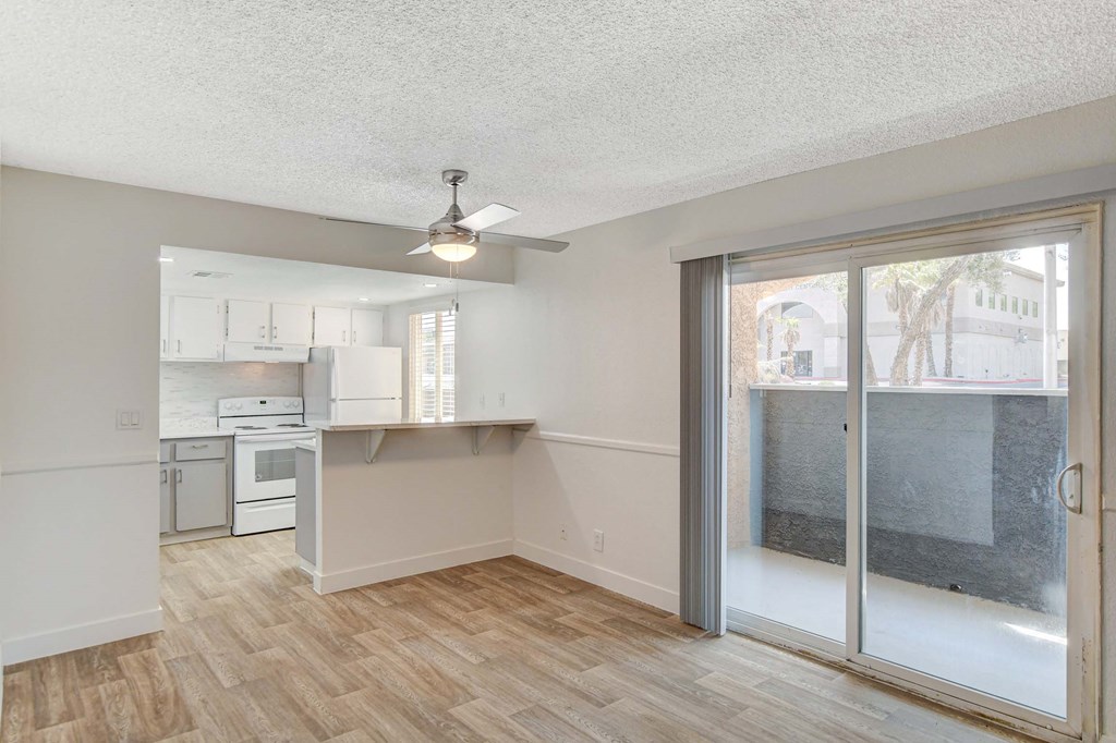 A room with a kitchen area and a sliding glass door.
