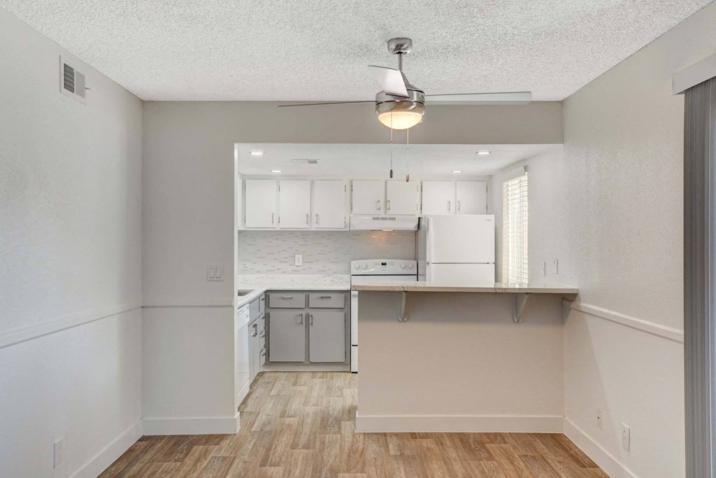 A kitchen with white cabinets and a wooden floor.