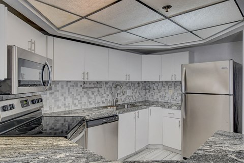A kitchen with white cabinets and a granite counter top.
