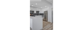 A modern kitchen with a white island and stainless steel appliances.