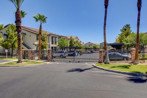 A street view of a gated community with palm trees and houses.