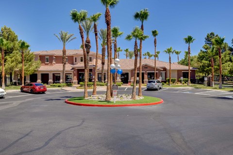 A roundabout with a sign in the middle of it and palm trees around it.