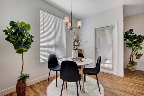 A dining room with a table, chairs, and a potted plant.