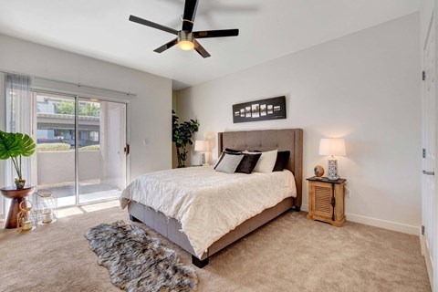 A bedroom with a large bed and a ceiling fan.