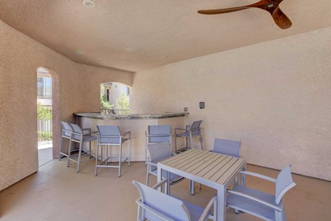 A patio with a table and chairs and a fan.