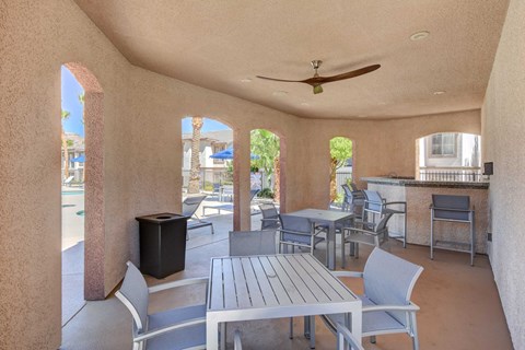 A patio with a table and chairs and a ceiling fan.
