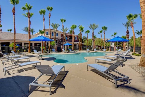A pool surrounded by palm trees and sun loungers.