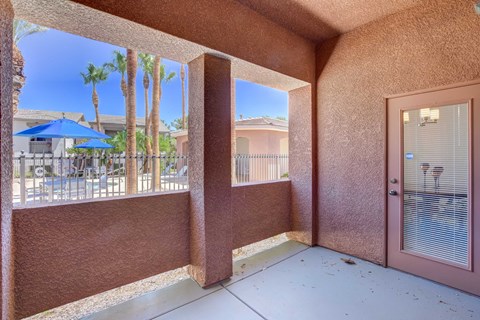 A balcony with a view of palm trees and a blue umbrella.