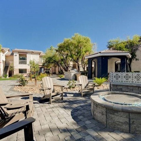A patio with a hot tub and chairs is surrounded by a stone wall.