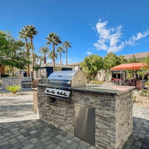 A stone outdoor kitchen with a grill and a sink.